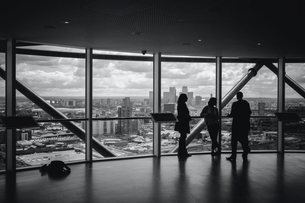 3 people stood in front of a glass windows on top of a building